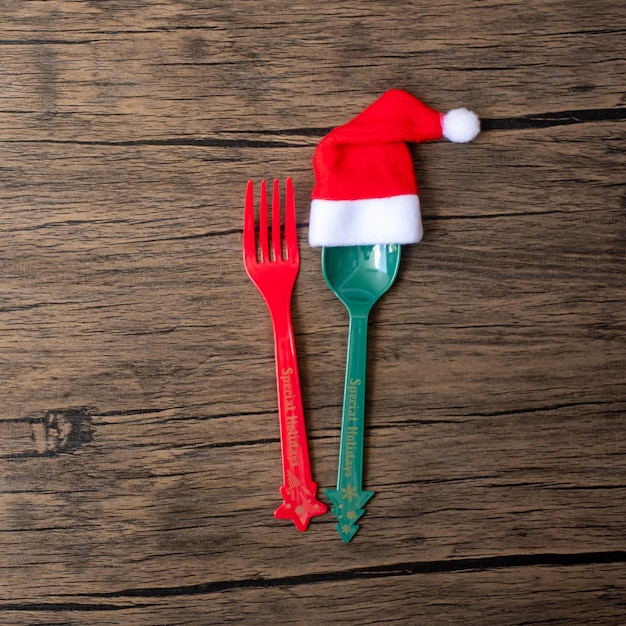 Merry Christmas with miniature Santa Claus, fork and spoon on wood table background. Xmas, party and happy New Year concept