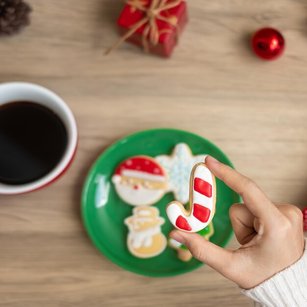 テーブル クリスマスイブ パーティー休日と幸せな新年の概念にコーヒー カップと自家製クッキーを持っている女性の手でメリー クリスマス