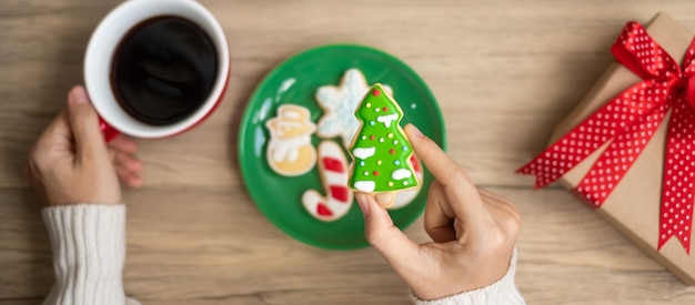 Merry Christmas with woman hand holding coffee cup and homemade cookie on table Xmas eve party holiday and happy New Year concept