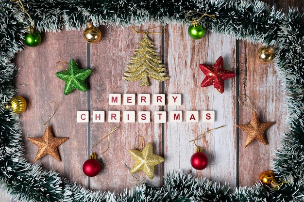 Buon natale scritto con lettere di un gioco e ornamenti di natale su uno sfondo di legno