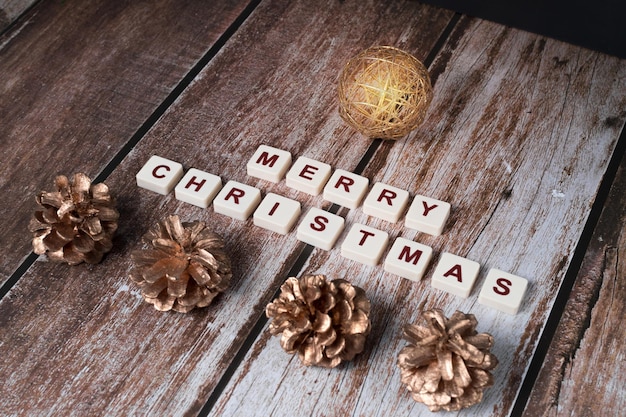 Merry Christmas written with letters of a set and Christmas ornaments with sparkle on a wooden background