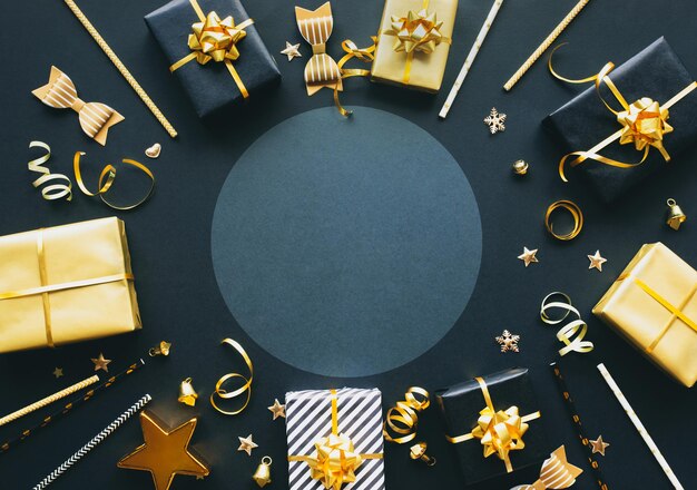 Concetti di buon natale, natale e capodanno con confezione regalo e ornamento in colore dorato su sfondo scuro stagione invernale e giorno dell'anniversario