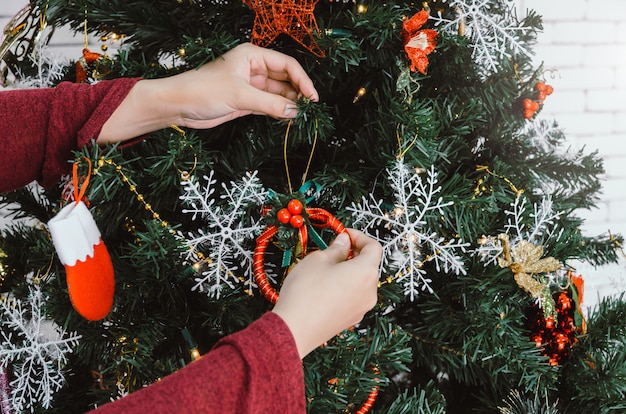 写真 メリークリスマス。自宅の美しいクリスマスに飾る赤いセーターの若い女性の手