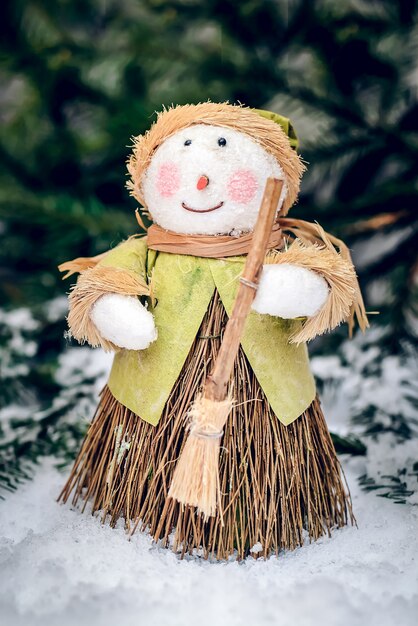 Merry Christmas zelfgemaakte sneeuwpop met bezem stands en glimlacht in de sneeuw