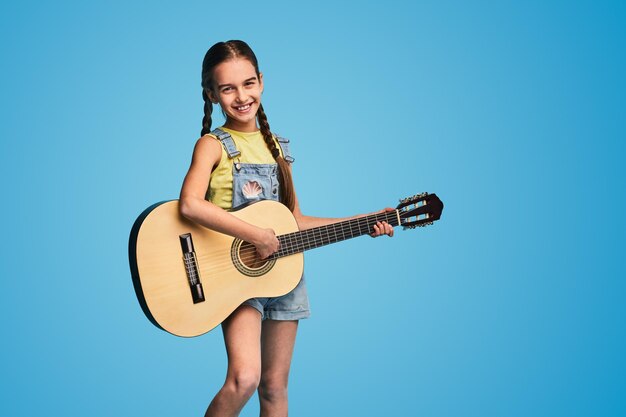 Merry girl playing guitar and smiling