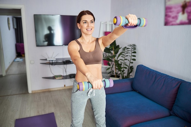 Merry pretty woman training shoulders at home