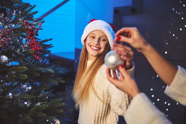 Merry teenage girl decorating house before Christmas