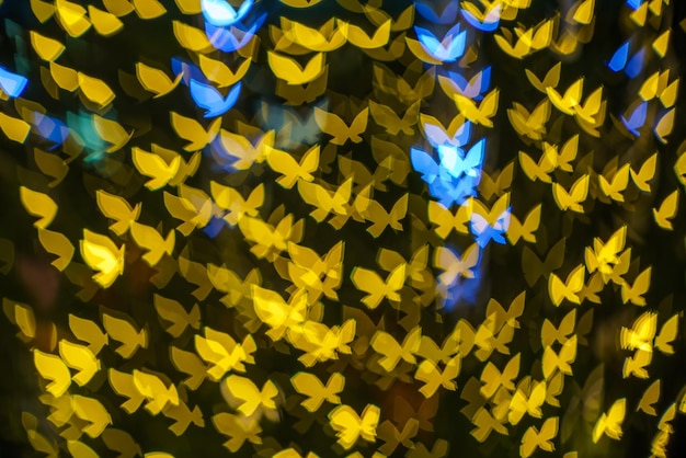 陽気なx-mas、黄色のカラフルな光ライトトンネルの抽象的な蝶のボケクリスマスツリーの背景クリスマスと愛の新年祭のイルミネーションの装飾。