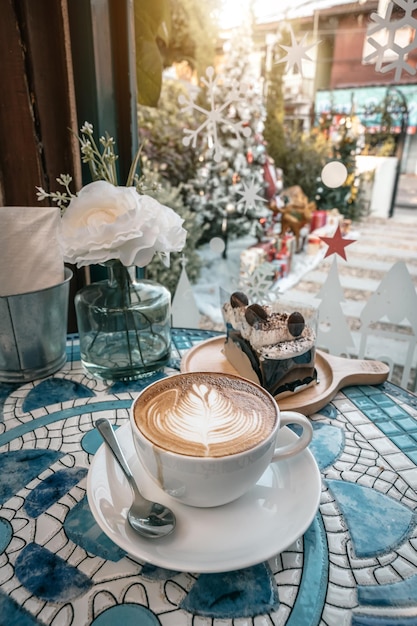 Merry xmashot coffee latte met latte art melkschuim in bekermok en zelfgemaakte chocoladetaart met kerstdecors en kerstballen op marmeren vloerbureau prettige kerstdagen en nieuwjaar vieren