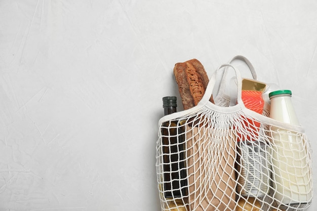 Mesh bag with different products on light grey background space for text