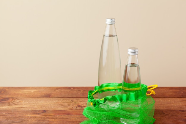 再利用可能なガラス製ウォーターボトル付きメッシュバッグ。持続可能なライフスタイル。廃棄物ゼロのコンセプト。プラスチックなし。