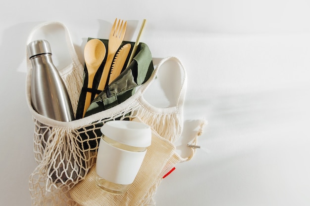 Mesh market bag with bamboo cutlery, reusable coffee mug  and  water bottle.    