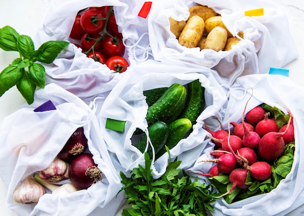 Mesh shopping bag with organic vegetables on marble background flat lay top view zero waste plastic free concept summer fruits