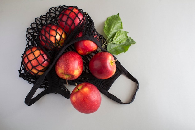 Mesh shopping bag with red apples on the gray background No plastic bag concept Top view Copy space