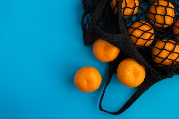 Mesh shopping black bag with tangerines on blue