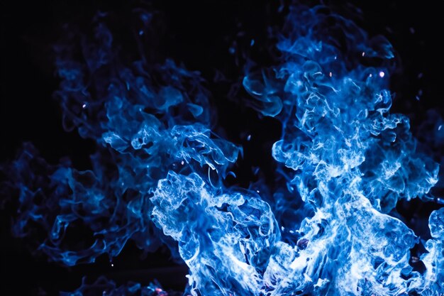 Foto le affascinanti fiamme blu danzavano graziosamente sullo sfondo nero come il fango.