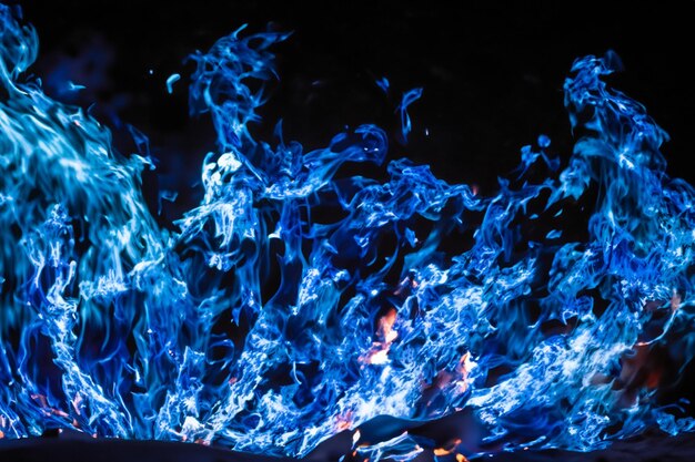매혹적인 파란 불꽃은 검은 배경에 우아하게 춤을 습니다.