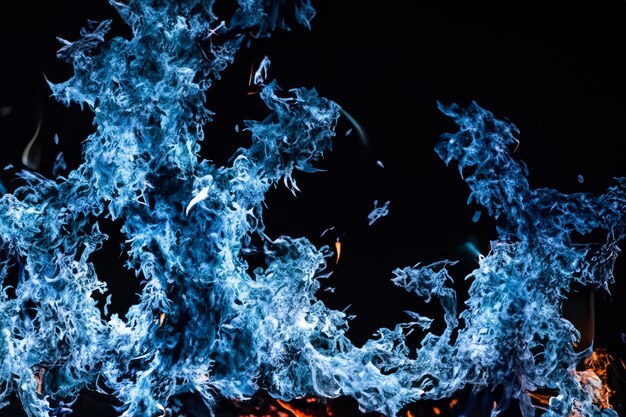 Foto le affascinanti fiamme blu danzavano graziosamente sullo sfondo nero come il fango.