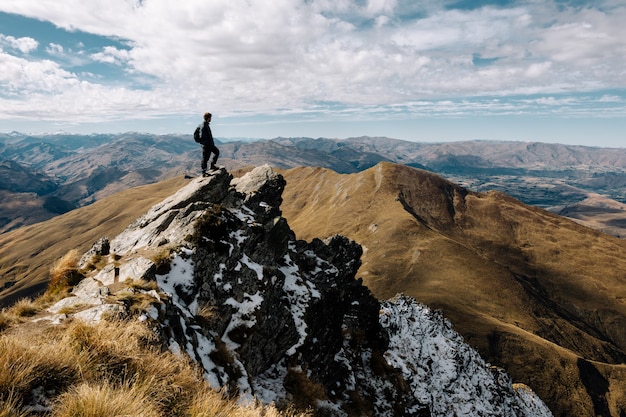 写真 昼間に山の頂上に立っている男性の魅惑的なショット