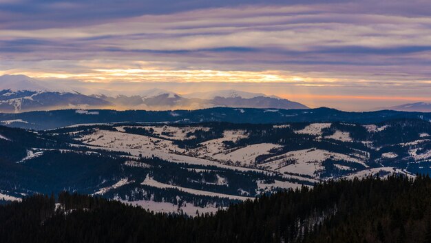 Mesmerizing views of snow-covered mountain ranges against backdrop of sunset and cloudy cloudy sky