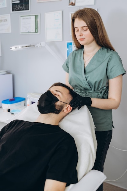 Mesotherapieprocedure Een schoonheidsspecialist voert een mesotherapieprocedure uit op het hoofd van een jonge man Haarversterking en -groei