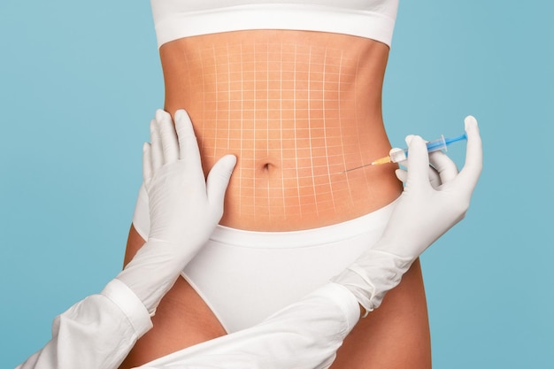 Mesotherapy concept unrecognizable doctor taking injection to abdomen of young woman