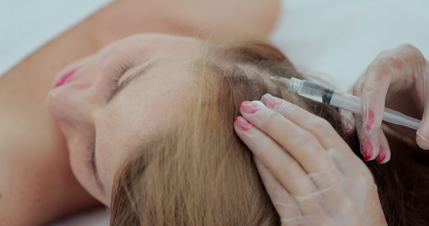 Mesotherapy for hair growth and strengthening in the beauty salon. The doctor makes injections into the scalp for hair growth.