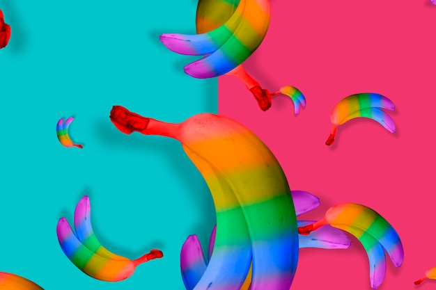 A mess of rainbow colored bananas on blue and pink background