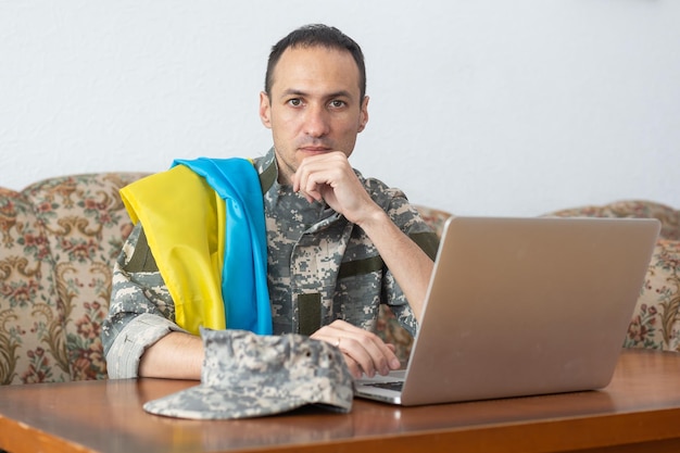 Foto messaggio per la pace nel mondo. militare con laptop e bandiera dell'ucraina