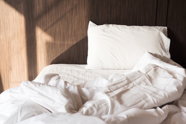 Messy bed. White pillow and blanket.