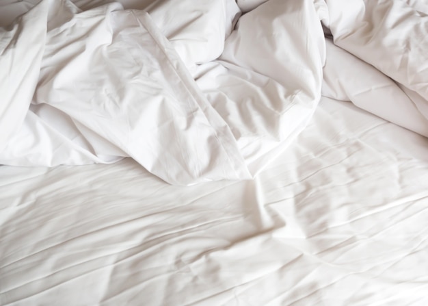 Messy bed. White pillow and blanket.