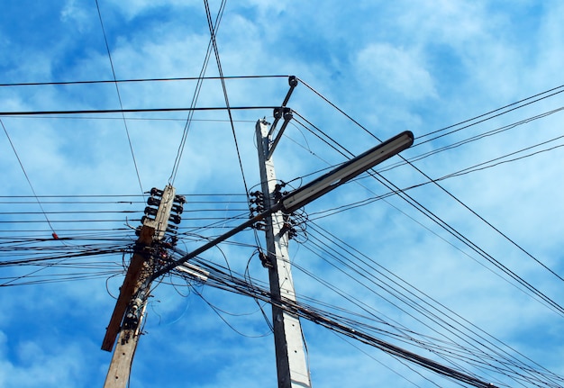 写真 乱雑な電気ケーブルと空を背景に電柱のワイヤー。