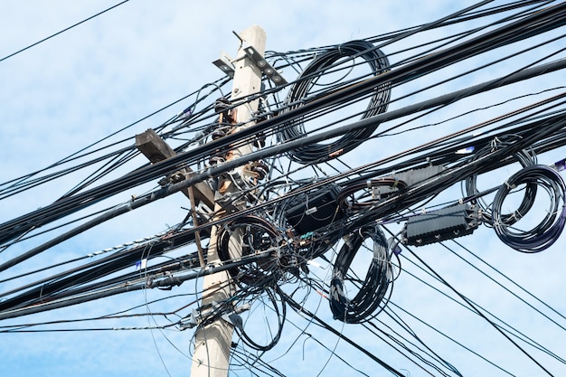 Messy electrical cables in thailand - many lines of cables\
chaotic set of interwoven, optical fiber technology open air\
outdoors.