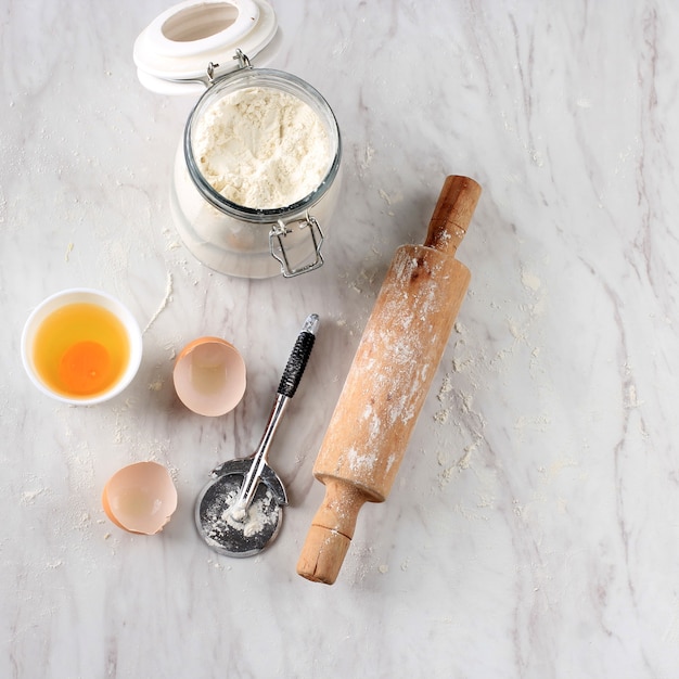 Messy Kitchen, After Baking Preparation at Marble Table. Flour, ROlling Pin, Egg, Pizza Cutter with Copy Space for Text