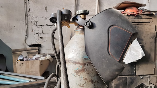 Messy old welding mask and equipment indoors with workshop background.