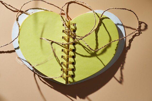 Фото Беспорядочная запутанная льняная нить на пустом сердечном блокноте