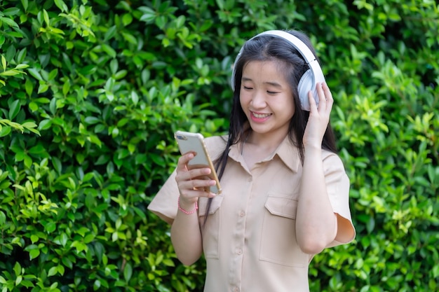 Foto met behulp van een smartphone met een mobiele telefoon apparaat met het dragen van witte draadloze koptelefoon en luisteren