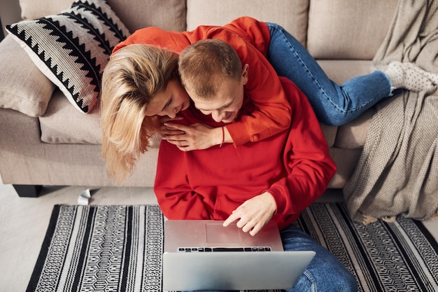 Met behulp van laptop die op de benen staat Jong mooi stel samen thuis weekend en vakantie samen doorbrengen