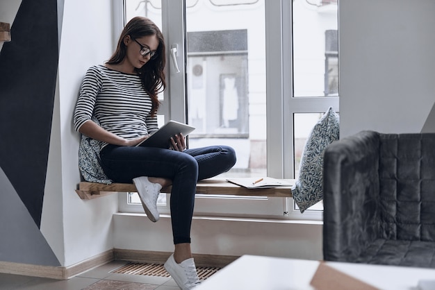 Met behulp van moderne technologieën. aantrekkelijke jonge vrouw die digitale tablet gebruikt