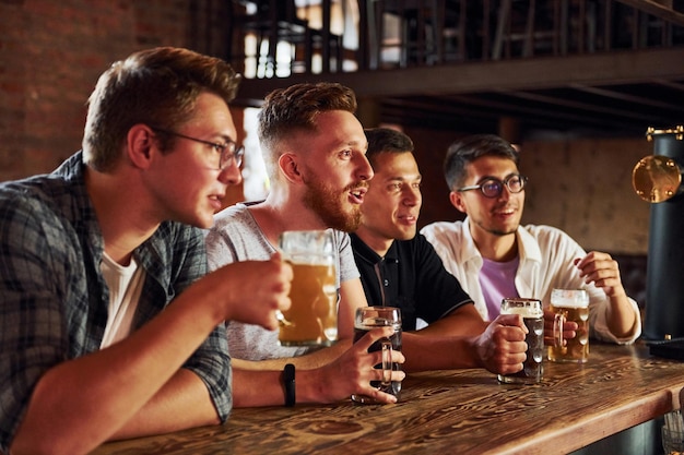Met bier in handen Mensen in vrijetijdskleding zitten in de kroeg