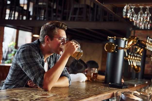 Met bier Man in vrijetijdskleding zittend in de kroeg