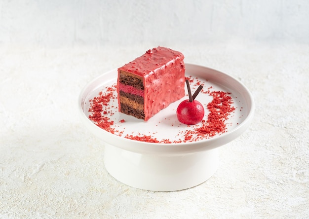 Met chocolade bedekte kersencake. Biscuitgebak met een laagje kersengelei met chocolademousse. Afgewerkt met kruimels en chocolade. Op een witte plaat. Lichte achtergrond.