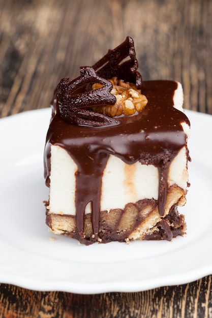 Met chocoladeroom bedekte slagroomtaart met biscuit, kubusvormige cake op een bord