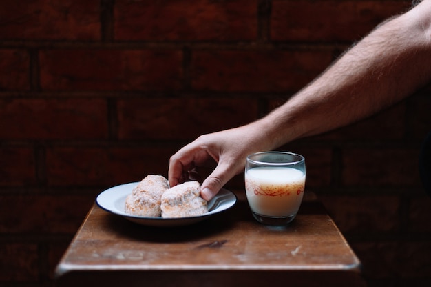 Met de hand een snoepje oppakken van tafel en een glas melk naast het bord