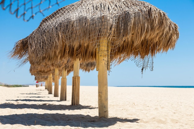 Met de hand gemaakte parasols van stro op een strand van de Zee van Cortez in San Jose del Cabo, Mexico