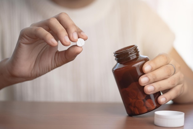 Foto met de hand medicijnen uit een bruine fles nemen