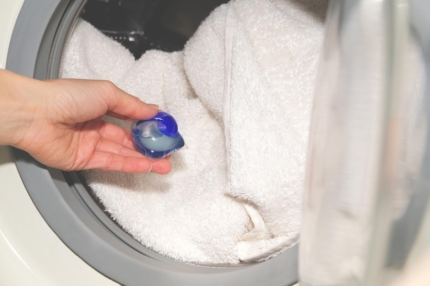 Met de hand op wasmiddelcapsule in witte katoenen handdoeken in de wasmachine gezet