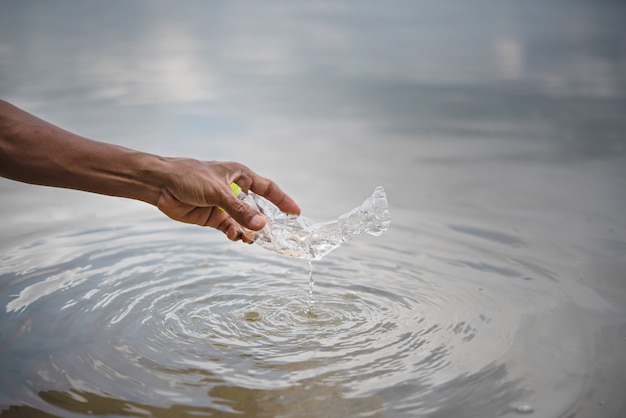 Met de hand plastic fles uit water halen