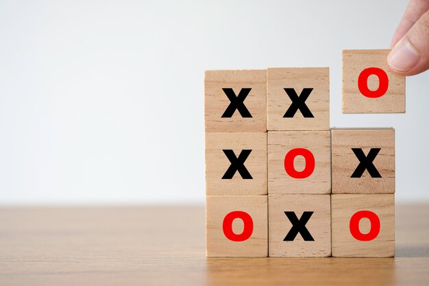 Met de hand zetten van een houten kubusblok met scherm "O" voor O- en X-spel of tic-tac-toe-elementen.