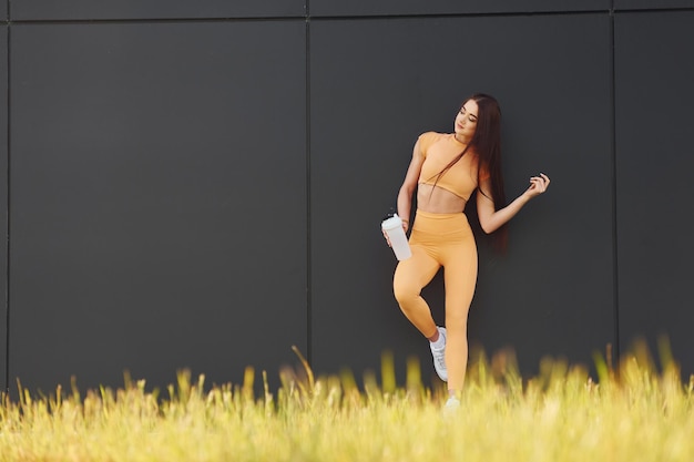 Met een fles water Jonge vrouw in sportkleding heeft buiten fitnesssessie